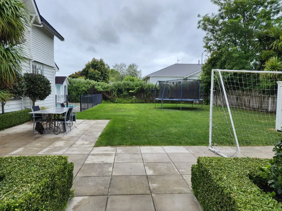 Fresh-cut backyard lawn with a paved patio and hedges