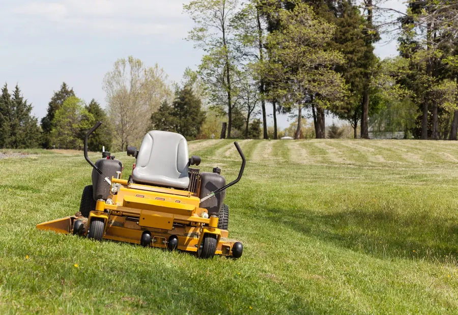 Ride-on mower leaving stripes across a large freshly cut lawn