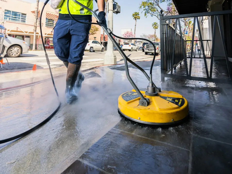 Worker pressure washing concrete with a surface cleaner